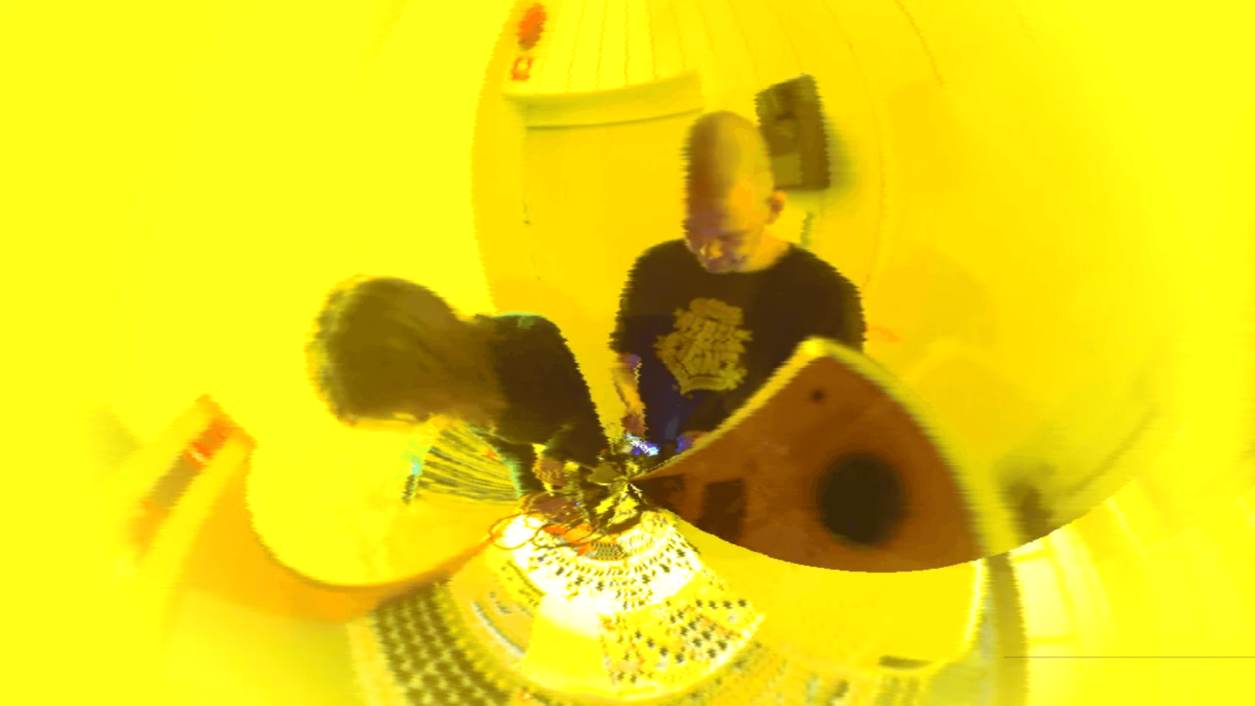 Two people are working with audio equipment in a brightly yellow-tinted, distorted image.