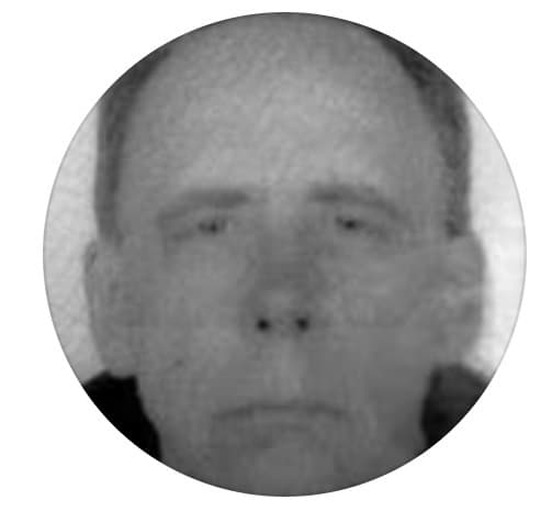 The image shows a grayscale, blurred portrait of a man with a neutral expression.
